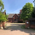 Hof Holthöfer Backsteinbau im ländlichen Stil mit gepflastertem Hof, umgeben von grünen Bäumen und gestrichenen Toren.