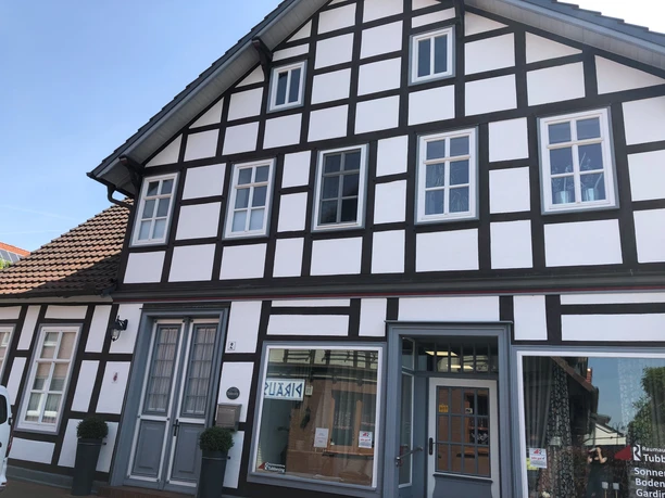 Gästezimmer Anna und Heini Historisches Fachwerkhaus mit weißer Fassade und dunklen Balken, großer Eingang und mehrere Fenster.