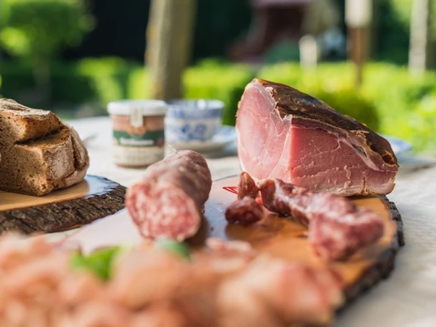 Hümmlinger Hofspezialitäten_2.jpg Aufgeschnittene Wurst und Schinken mit Bauernbrot auf Holzbrett im Freien angerichtet