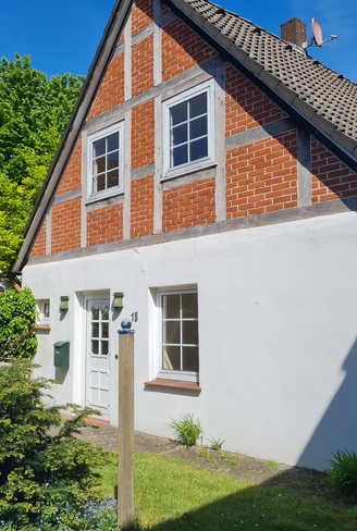 Fachwerkhaus mit roter Backsteinfassade und weißen Putzwänden, umgeben von gepflegtem Garten.Half-timbered house with red brick façade and white plaster walls, surrounded by a well-kept garden.Bindingsværkshus med rød murstensfacade og hvide pudsede vægge, omgivet af en velplejet have.Vakwerkhuis met rode bakstenen gevel en wit gepleisterde muren, omgeven door een goed onderhouden tuin.