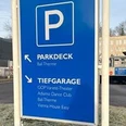 Parkhaus Morsbachallee.jpg Wegweiser zum Parkdeck und zur Tiefgarage, mit Hinweisen zu nahegelegenen Einrichtungen im Hintergrund.