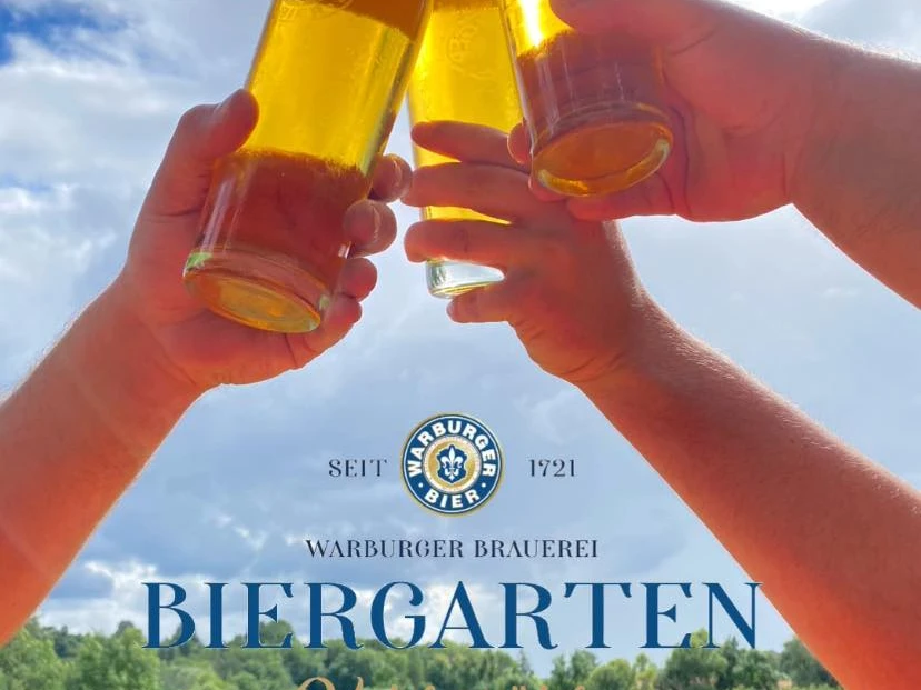 280688983_541883030869259_7393633277648066258_n.jpg Drei Hände stoßen mit halbvollen Biergläsern im Freien an; im Hintergrund sieht man den Himmel.