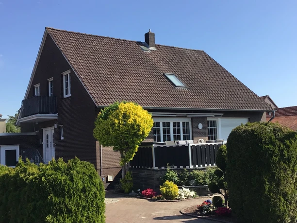 FeWo Kropp Ferienwohnung Kropp in einem zweigeschossigen Backsteinhaus, umgeben von gepflegtem Grün.