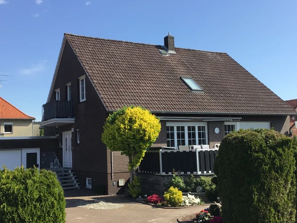 FeWo Kropp Ein Einfamilienhaus mit braunem Klinker und Satteldach, umgeben von gepflegten Gärten.