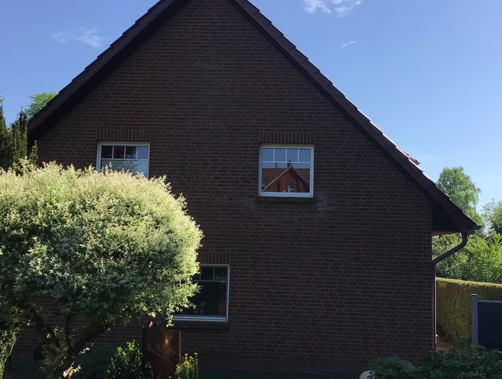 FeWo Brauer Backsteinhaus mit Steildach und gepflegtem Garten, diversen Pflanzen und einem kleinen Weg im Vordergrund.Brick house with pitched roof and well-kept garden, various plants and a small path in the foreground.Murstenshus med skråt tag og velplejet have, forskellige planter og en lille sti i forgrunden.Bakstenen huis met schuin dak en goed onderhouden tuin, verschillende planten en een klein pad op de voorgrond.