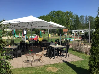 Gasthof und Hotel Rohrbach Sonnenterrasse mit Tischen, Stühlen und Sonnenschirmen im Grünen, umgeben von Bäumen und Spielplatz.