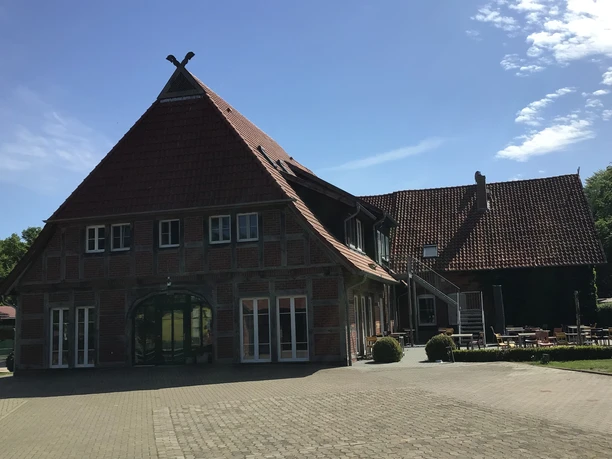 SpeicherKaffee Ein traditionelles Fachwerkhaus mit rotem Ziegeldach und gepflegtem Außenbereich unter blauem Himmel.