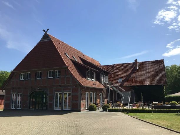 SpeicherKaffee Ein imposanter Backsteinbau mit roten Dachziegeln und einladender Terrasse unter blauem Himmel.