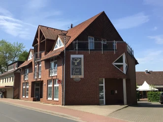 Een modern hotel met rode bakstenen en een opvallende gevel aan een rustige straat in de zon.