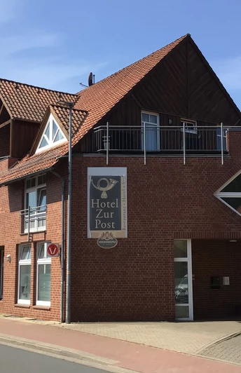 Ein modernes Hotel mit rotem Backstein und markantem Giebel an einer ruhigen Straße im Sonnenschein.A modern hotel with red brick and a striking gable on a quiet street in the sunshine.Et moderne hotel med røde mursten og en markant gavl på en stille gade i solskin.Een modern hotel met rode bakstenen en een opvallende gevel aan een rustige straat in de zon.