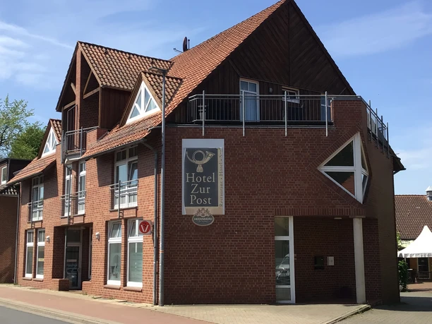 Rood bakstenen gebouw van Hotel zur Post met opvallende dakconstructie en uitnodigend balkon.