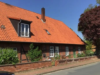 Ferienwohnung Runge Rotes Ziegelbauernhaus mit markantem Giebeldach und grünem Garten unter blauem Himmel.Red brick farmhouse with striking gabled roof and green garden under a blue sky.Rød murstensgård med markant sadeltag og grøn have under en blå himmel.Boerderij van rode baksteen met opvallend zadeldak en groene tuin onder een blauwe hemel.