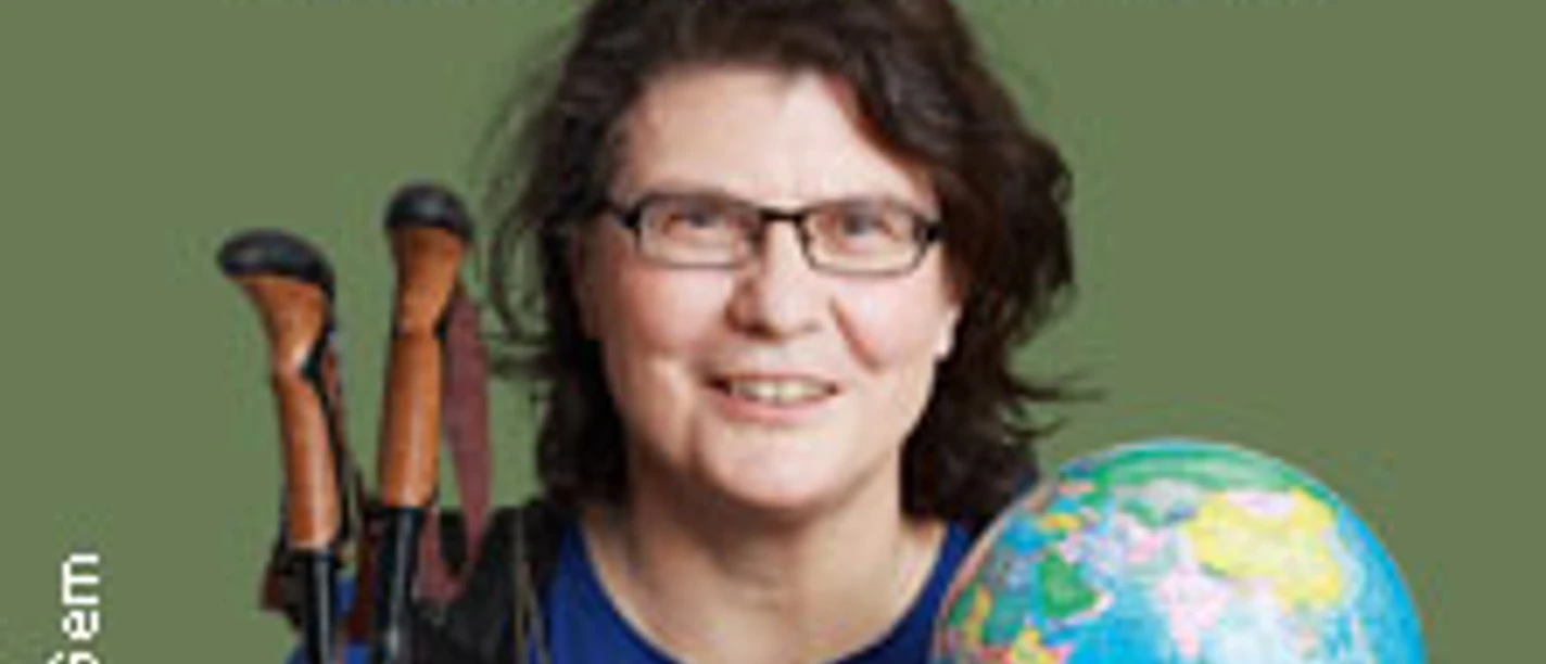 Christine Thürmer lächelt mit Wanderstöcken und Globus in den Händen vor einem grünen Hintergrund.