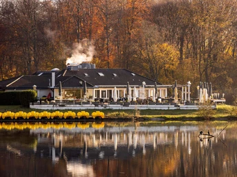Decksteiner Weiher Ein herbstlich gefärbter Wald umrahmt ein charmantes Gebäude am Decksteiner Weiher, dessen Wasser die Umgebung spiegelt.An autumn-coloured forest frames a charming building on the Decksteiner Weiher pond, whose water reflects the surroundings.