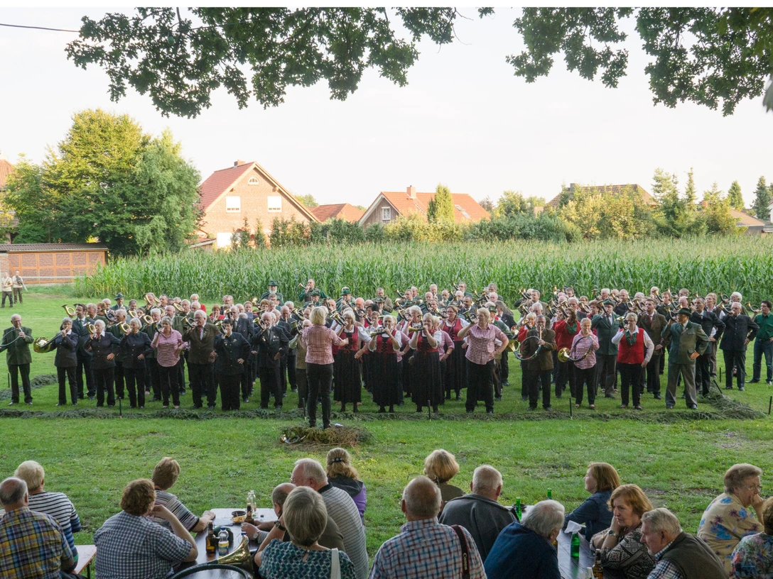 jaegerabend-bispingen-behringen.jpg Eine große Gruppe in Trachten spielt im Freien Blasmusik vor einem Publikum bei einem Fest.