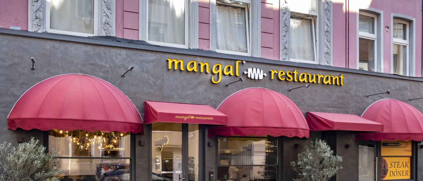 Mangal Restaurant Exterior view with red canopy and elegant façade in an urban setting.