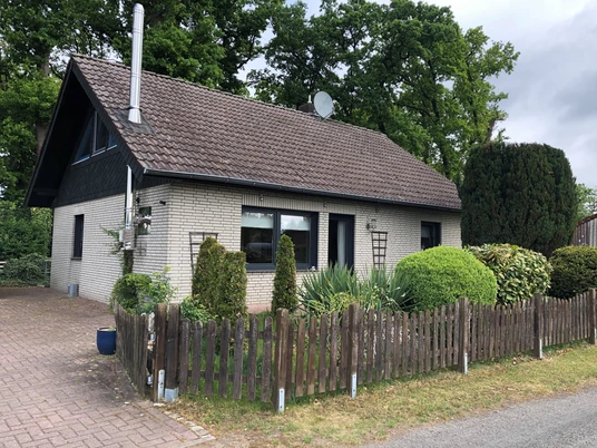 Idylle zwischen Weser und Moor Ein einladendes Backsteinhaus mit Satteldach, von Hecken und Büschen eingerahmt, in grüner Umgebung.An inviting brick house with a pitched roof, framed by hedges and bushes, in green surroundings.Et indbydende murstenshus med skråt tag, indrammet af hække og buske, i grønne omgivelser.Een uitnodigend bakstenen huis met een schuin dak, omringd door heggen en struiken, in een groene omgeving.