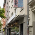 Mashery Hummus Kitchen Mashery Hummus Kitchen ist in einer belebten Kölner Straße gelegen. Außenansicht mit modernen Fassaden und einem markanten Logo zeigt den Eingang.