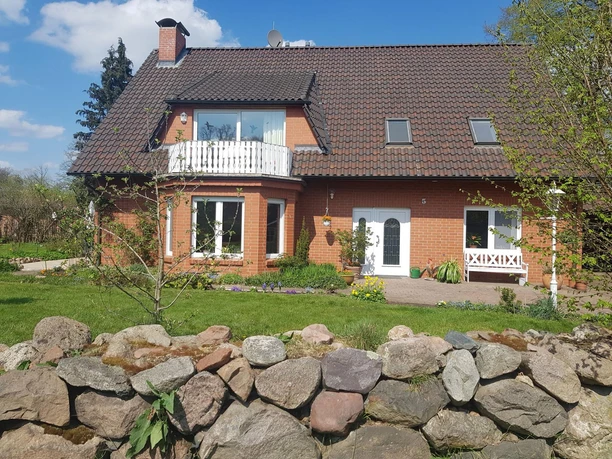 Außenansicht Außenansicht der Ferienwohnung Kühn mit Garten, Steimauer und Balkon bei sonnigem Wetter.