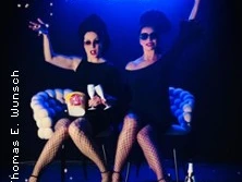 Zwei Performerinnen in schwarzen Outfits und Sonnenbrillen, feiern mit Champagner vor "JukeBoxDivas".