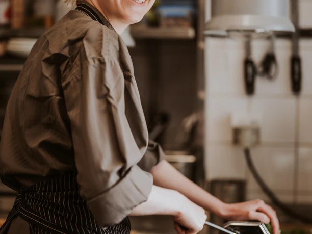 Eine lachende Köchin arbeitet an einer Teigmaschine in einer professionellen Küchenküche.