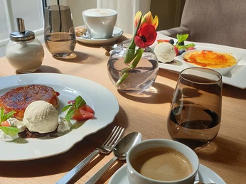 am-osterfeuer-4.jpg Ein gedeckter Tisch mit Desserts: Crème brûlée und Eis mit Beeren. Elegantes Gedeck mit Kaffee.