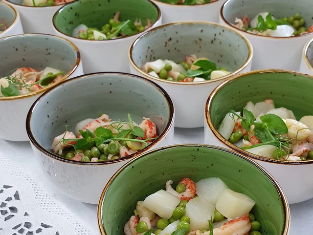 am-osterfeuer-7.jpg Mehrere Schalen mit Spargelsalat, Garnelen, Erbsen und Kräutern, auf einem Tisch angerichtet.