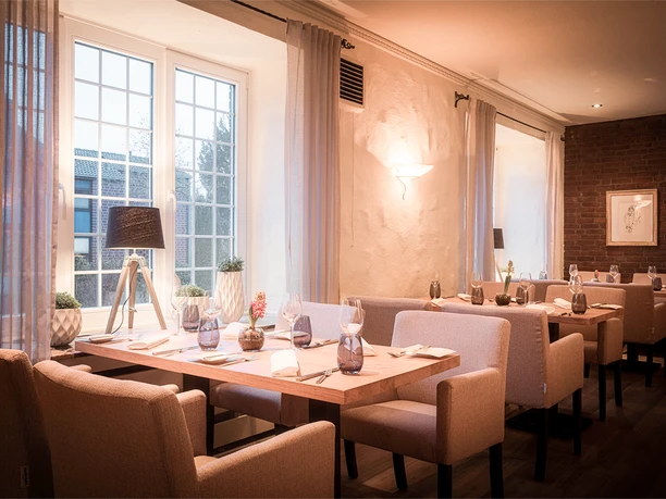 Ein stilvoll eingerichtetes Restaurant mit warmem Licht, gedeckten Tischen und großen Fenstern.