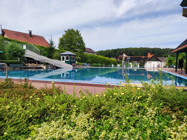 Waldfreibad Preußisch Oldendorf Waldfreibad Preußisch Oldendorf mit großer Wasserrutsche, umgeben von grüner Natur und blauen Himmel.