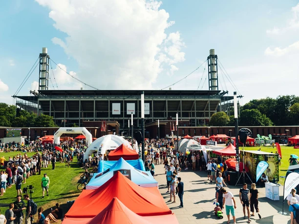 Lively outdoor sports and culture festival at the RheinEnergieStadion in Cologne. Numerous colourful tents and lots of people enliven the scene.