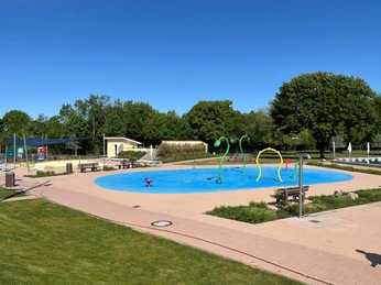 Moderner Wasserspielplatz im Freibad Achim mit bunten Wasserspritzfiguren und umliegender Grünfläche.