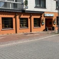 Rotes Gebäude mit großen Fenstern und Eingangsschild "Hellas", griechisches Restaurant in der Stadt.