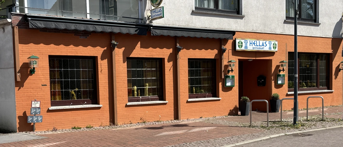 Restaurant Hellas Rotes Gebäude mit großen Fenstern und Eingangsschild "Hellas", griechisches Restaurant in der Stadt.