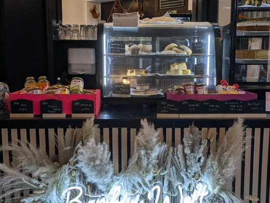 PXL_20241108_103529933.jpg Ein kleiner Verkaufsstand bietet Gebäck und Snacks an, dekoriert mit leuchtendem Schriftzug "Bambi Welt".