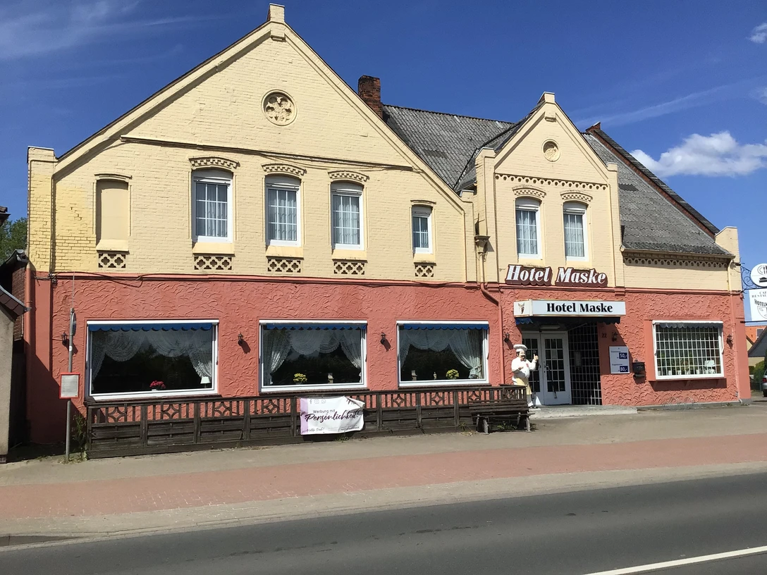 Hotel Maske Das Foto zeigt die Fassade des Hotel Maske in einem Backsteingebäude mit Zierelementen und Blumen.