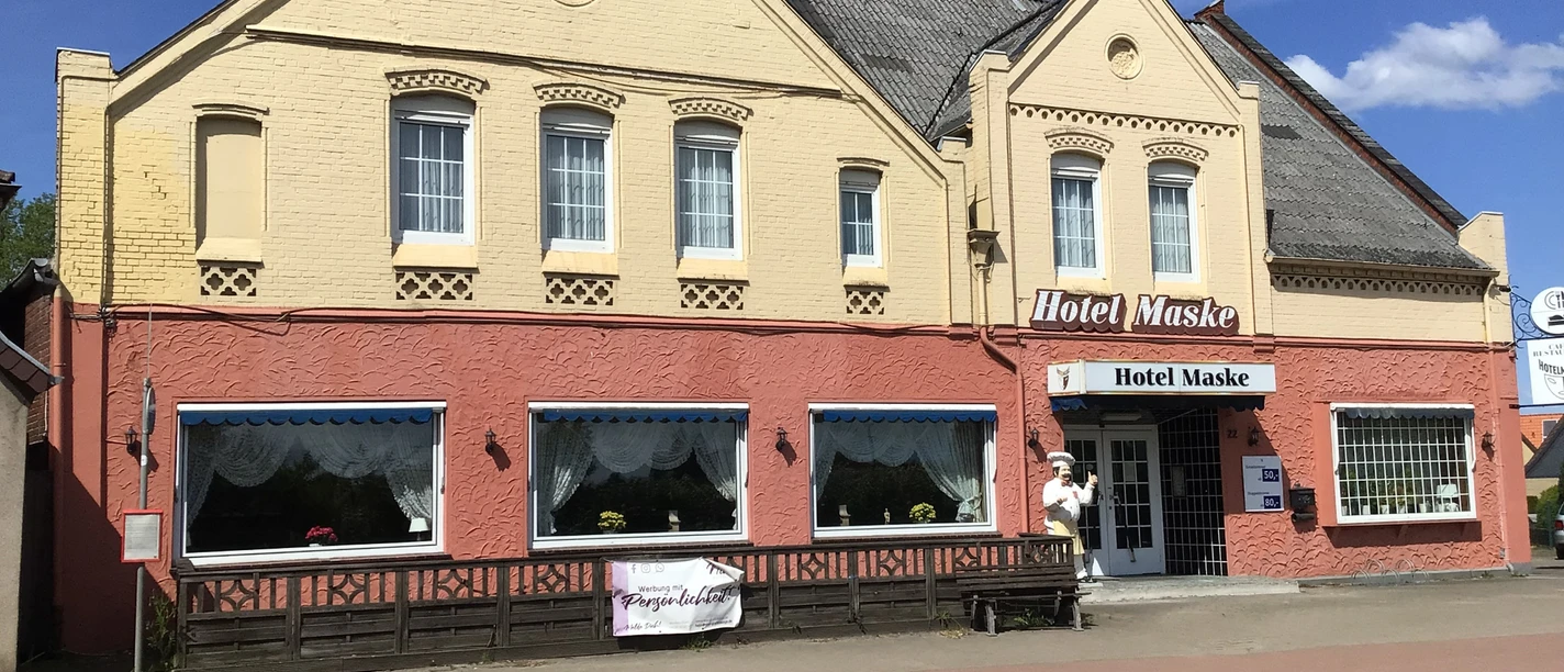 Hotel Maske Das Foto zeigt die Fassade des Hotel Maske in einem Backsteingebäude mit Zierelementen und Blumen.