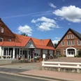 Traditionelles Landhotel mit Fachwerkarchitektur, umgeben von gemütlicher Terrasse und blauem Himmel.