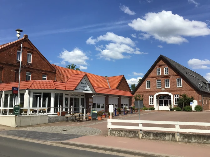 Traditional country hotel with half-timbered architecture, surrounded by a cozy terrace and blue sky.