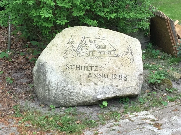 Reiterhof Schultz Reiterhof Schultz: Großer Stein mit Gravur eines Hauses und Tannen, darüber "Schultz Anno 1986".