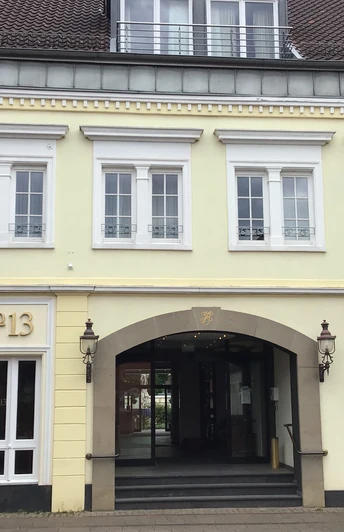 Historische Fassade von Hotel Höltje mit offenen Eingangsportal, darüber aufgereihte Fenster.