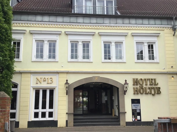 Historic façade of Hotel Höltje with open entrance portal, windows lined up above.