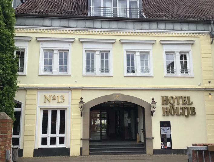 Hotel Höltje Historische Fassade von Hotel Höltje mit offenen Eingangsportal, darüber aufgereihte Fenster.Historic façade of Hotel Höltje with open entrance portal, windows lined up above.Historisk facade på Hotel Höltje med åben indgangsportal og vinduer på rad og række ovenover.Historische gevel van Hotel Höltje met open entreeportaal, ramen boven elkaar.