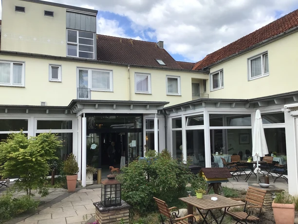 Hotel Höltje in Verden with inviting outdoor terrace, wooden furniture and green planting.