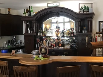 Ein holzgetäfelter Tresen vor einem gut bestückten, traditionellen Getränkeregal mit Spiegel.