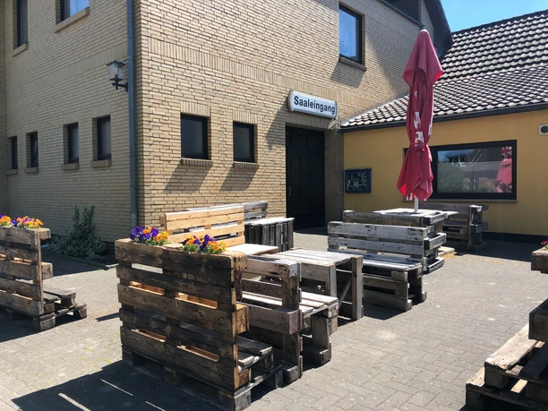 Buitenruimte van Döhlings Gasthaus met rustiek zitmeubilair gemaakt van pallets en een parasol.
