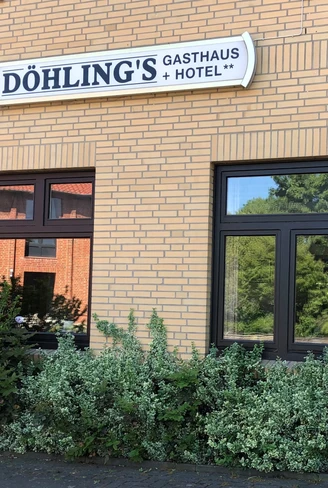 Döhlings Gasthaus mit seinem gelben Backstein und großen Fenstern, umgeben von üppigem Grün.