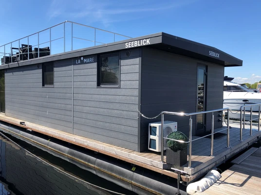 La Mare Hausboot Wieltsee Hausboot mit modernem Design und Dachterrasse auf ruhigem Gewässer unter einem klaren blauen Himmel.Houseboat with modern design and roof terrace on calm waters under a clear blue sky.Husbåd med moderne design og tagterrasse på roligt vand under en klar blå himmel.Woonboot met modern design en dakterras op kalm water onder een helderblauwe hemel.