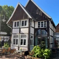 Museumscafé Gütersloh Fachwerkhaus mit Café-Terrasse, umgeben von grüner Bepflanzung und klarem Himmel.