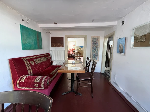 Museumscafé Gütersloh Innenansichten Ein gemütliches Wohnzimmer mit einem roten Sofa, einem Holztisch und dekorativen Bildern an den Wänden.