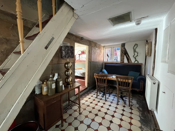 Museumscafé Gütersloh Innenansichten Gemütlicher Innenraum mit rustikalen Holzmöbeln, Fliesenboden und Treppe, Tischgruppe lädt zum Verweilen ein.